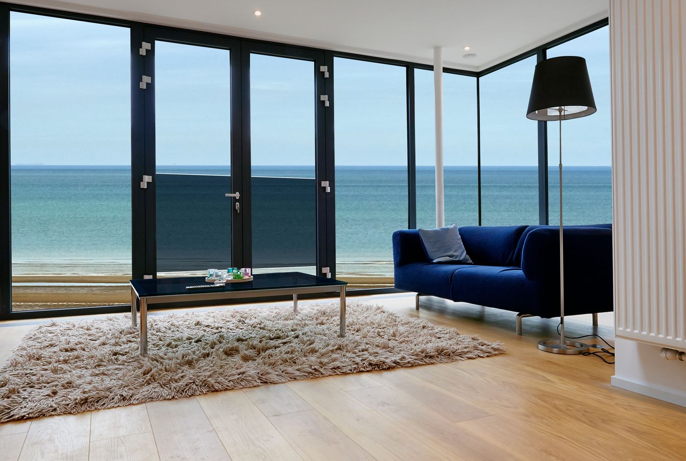 A living room with wide windows over the ocean, the Superior apartment
